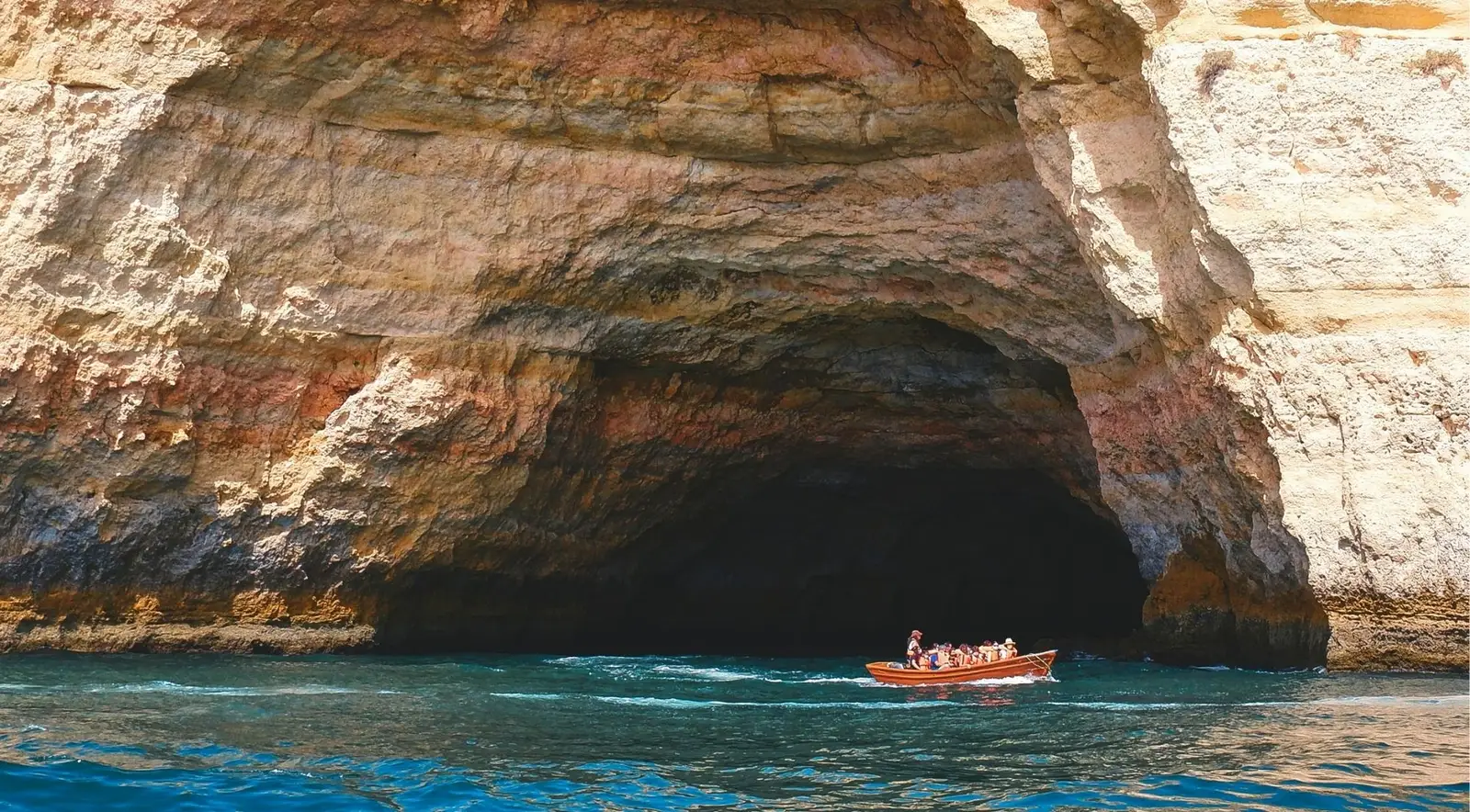 A cruise boat passing below the golden Algarve cliffs on a calm Atlantic evening