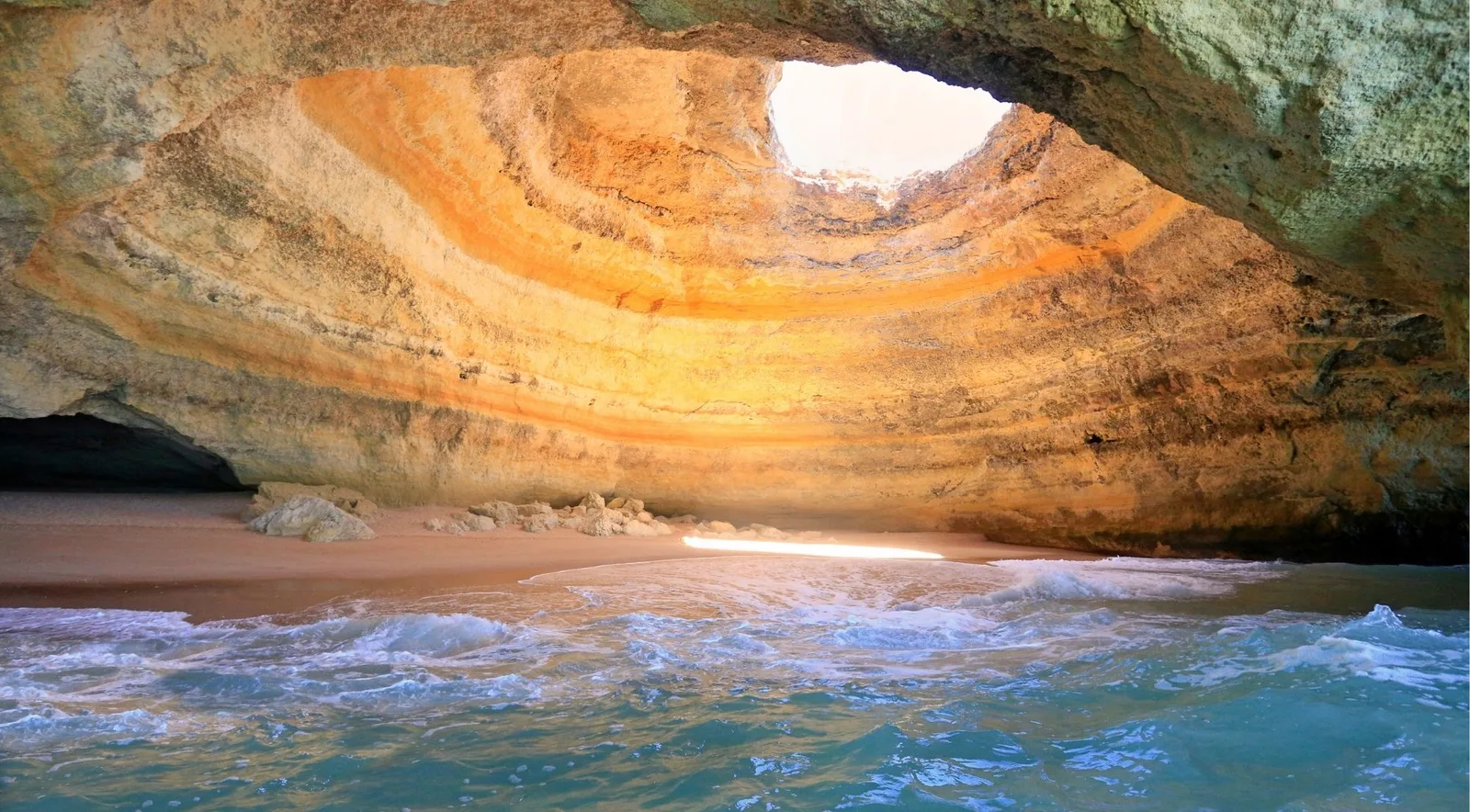 The golden domed interior of Benagil Cave illuminated by the skylight, the destination of boat tours departing from Albufeira Marina 18 km west along the Algarve coast